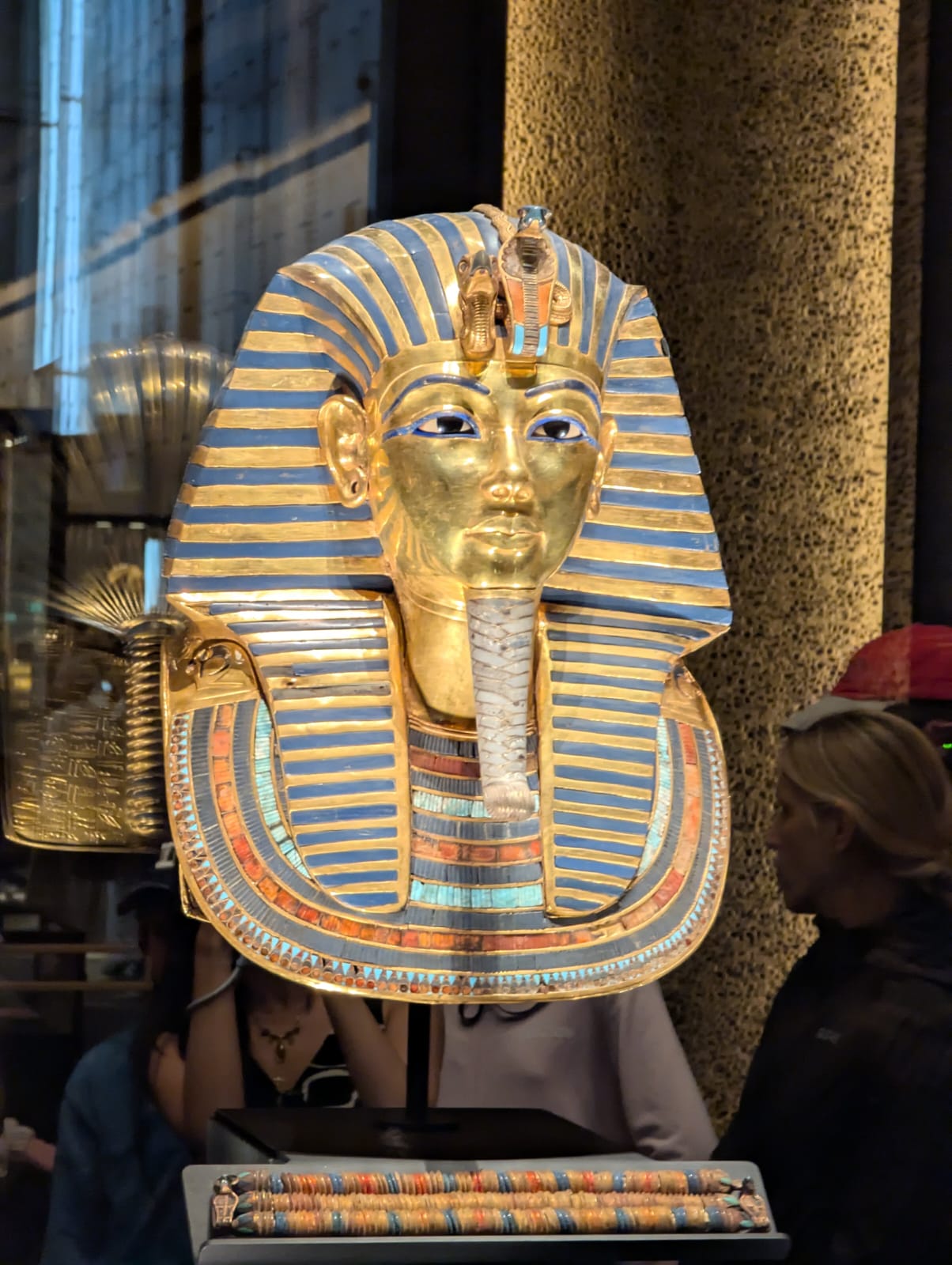 A rooftop terrace with wooden outdoor furniture on patterned tiles, overlooking a sunset and distant landscape.