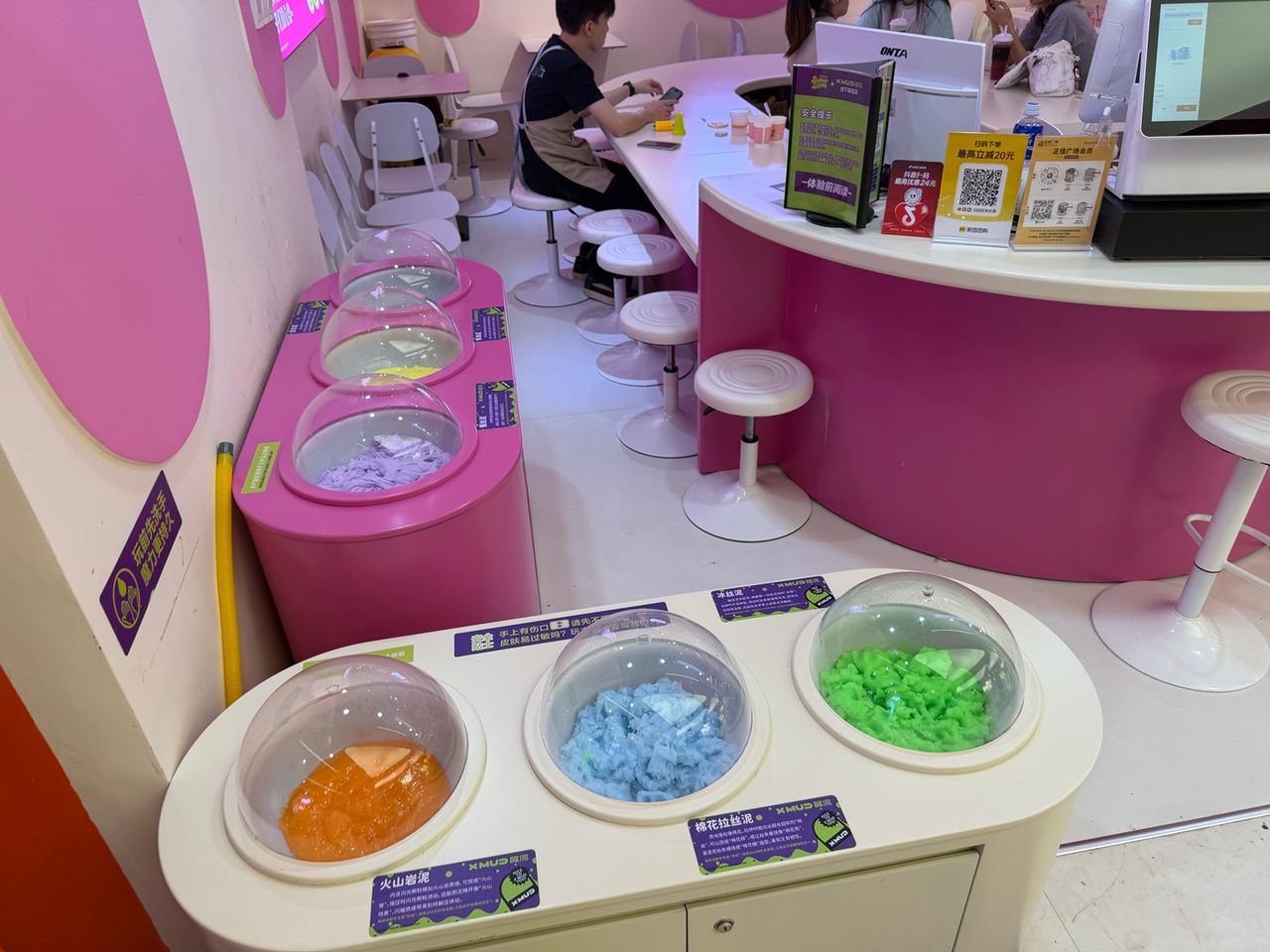 Photo terrain STORIMITIK montrant plusieurs textures et couleurs de slime présentées sous des cloches dans une boutique Super Slime.