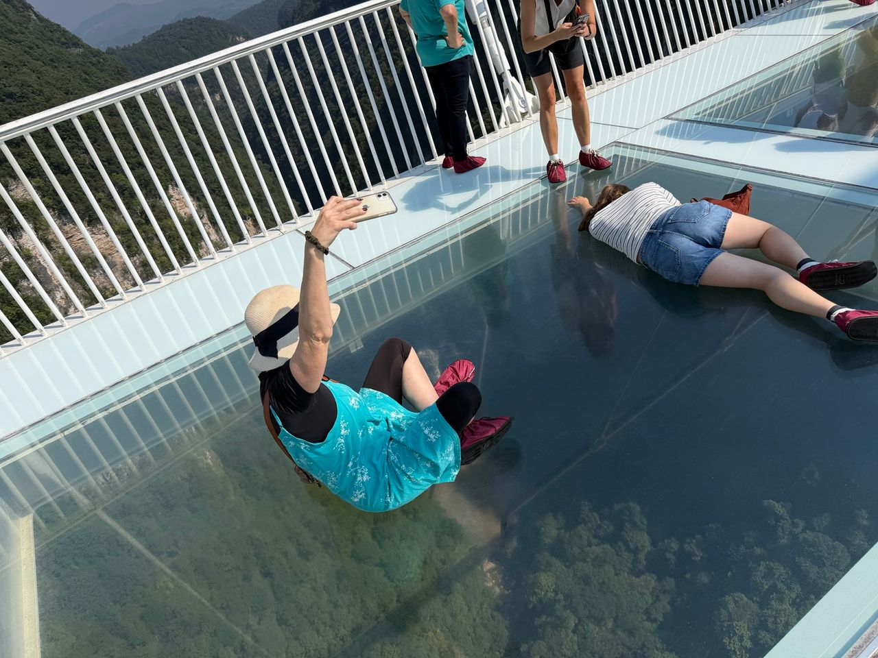 Visiteurs allongés sur le plancher de verre du pont de Zhangjiajie.