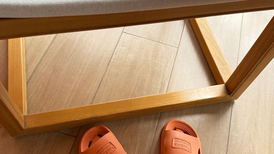iPhone dans une coque orange posé à côté d’une paire de tongs orange, utilisées comme clin d’œil visuel à l’écosystème d’accessoires Apple.