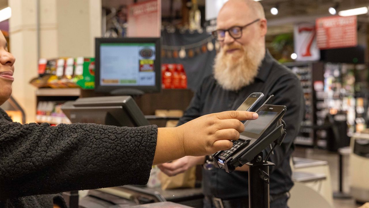 Client utilisant une application mobile pour payer ses achats alimentaires dans un supermarché à Seattle.