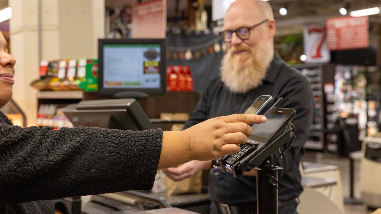 Client utilisant une application mobile pour payer ses achats alimentaires dans un supermarché à Seattle.