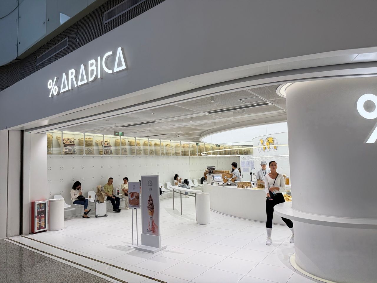 Entrée du café % Arabica à l’aéroport international de Guangzhou Baiyun, dominée par une grande enseigne blanche et le symbole pourcentage.