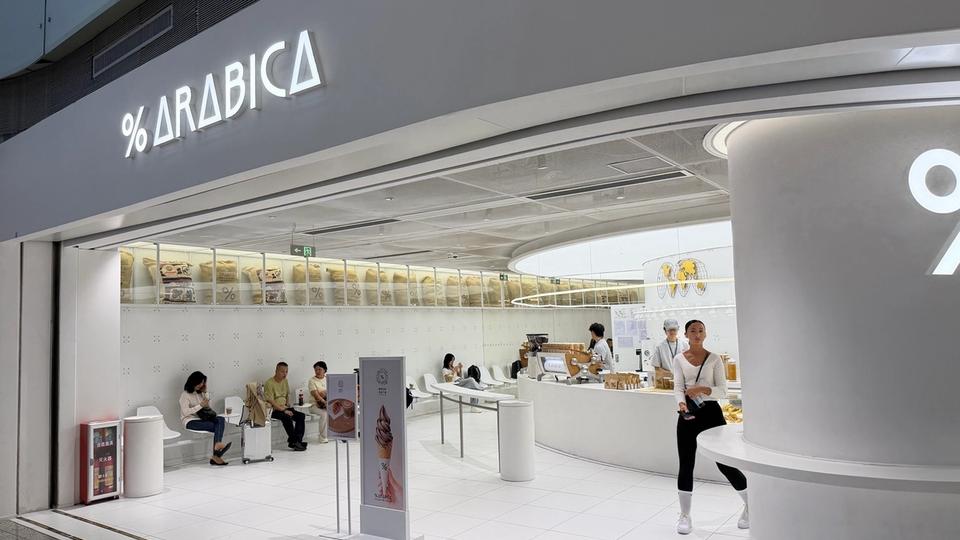 Entrée du café % Arabica à l’aéroport international de Guangzhou Baiyun, dominée par une grande enseigne blanche et le symbole pourcentage.
