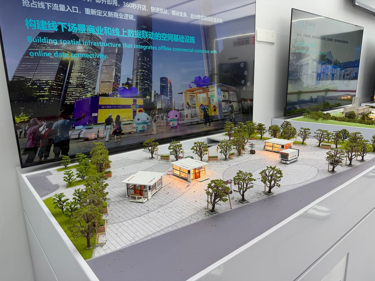 Photo terrain STORIMITIK d’une maquette urbaine FlexBot M‑SPACE montrant plusieurs modules mobiles installés sur une place.
