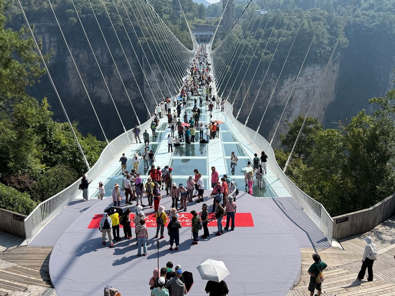Câbles visibles dans le relief de Tianmen Mountain avec visiteurs au premier plan.