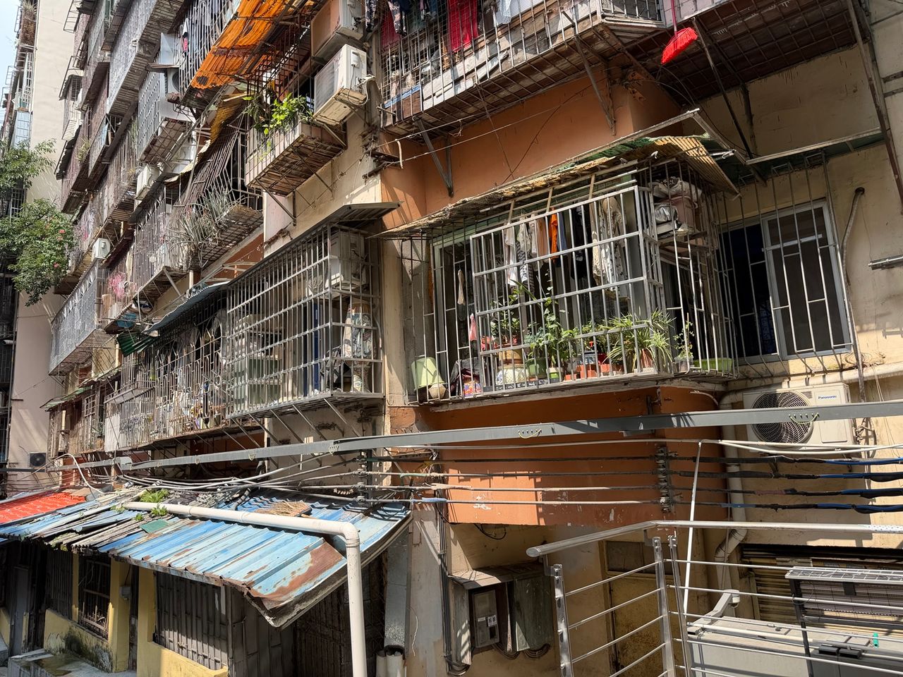 Photo terrain d’un ensemble résidentiel ancien de Guangzhou avec balcons grillagés et climatiseurs.