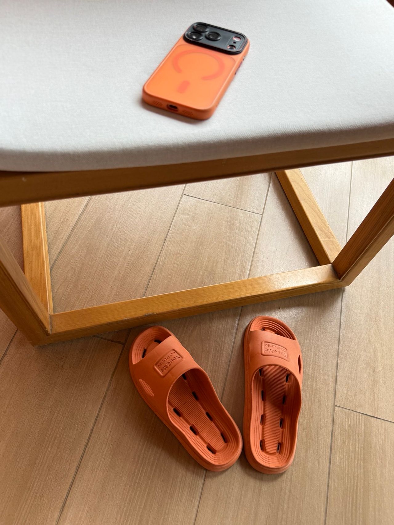 iPhone avec coque orange et tongs orange photographiés ensemble.