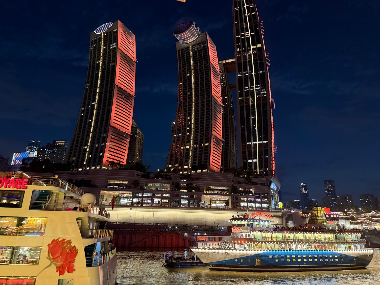 Vue nocturne de Raffles City Chongqing avec plusieurs tours et The Crystal, structure horizontale reliant les gratte-ciel.