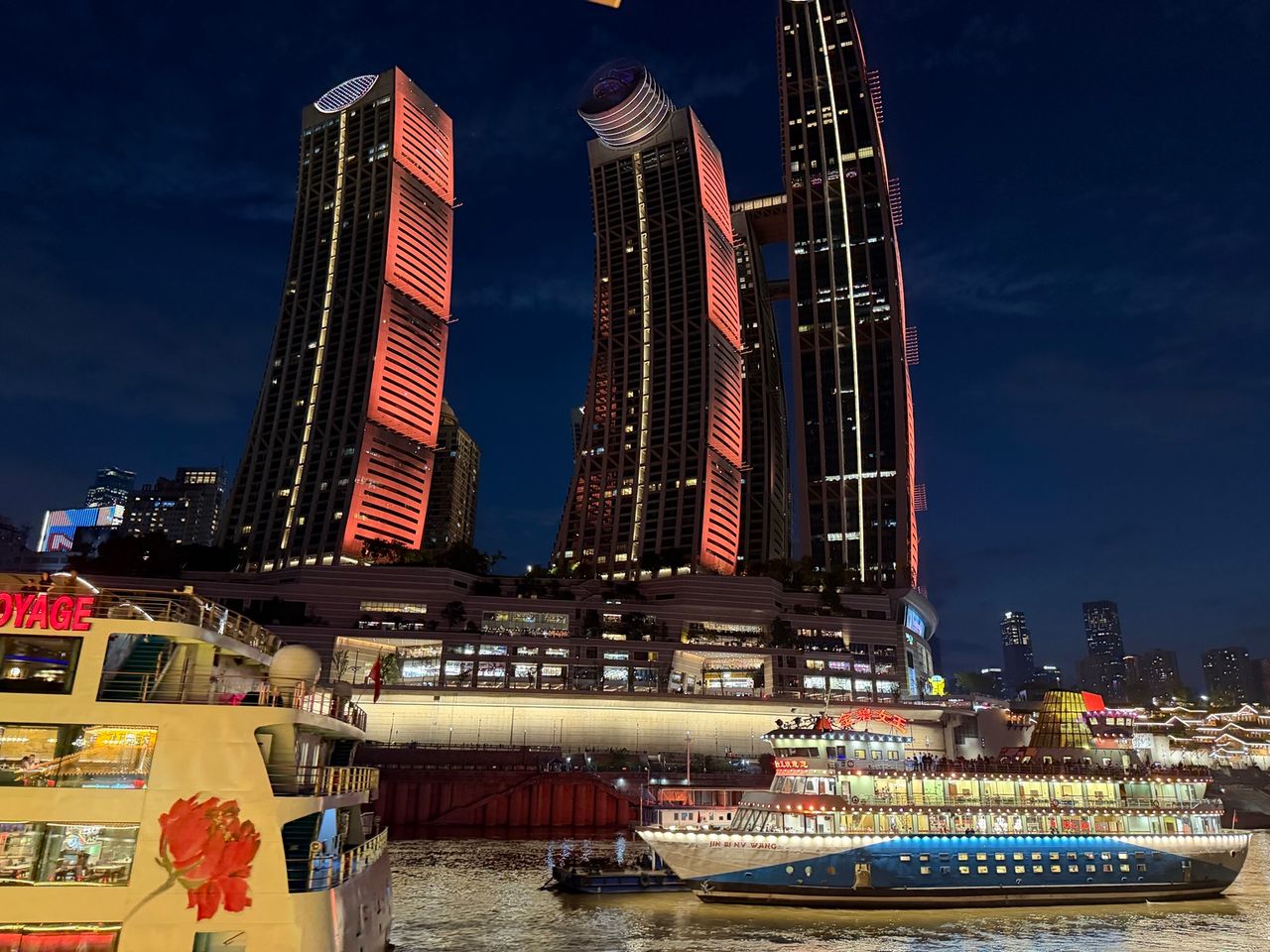 Vue nocturne de Raffles City Chongqing avec plusieurs tours et The Crystal, structure horizontale reliant les gratte-ciel.