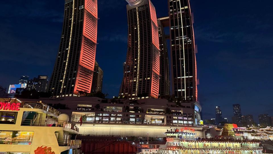 Vue nocturne de Raffles City Chongqing avec plusieurs tours et The Crystal, structure horizontale reliant les gratte-ciel.