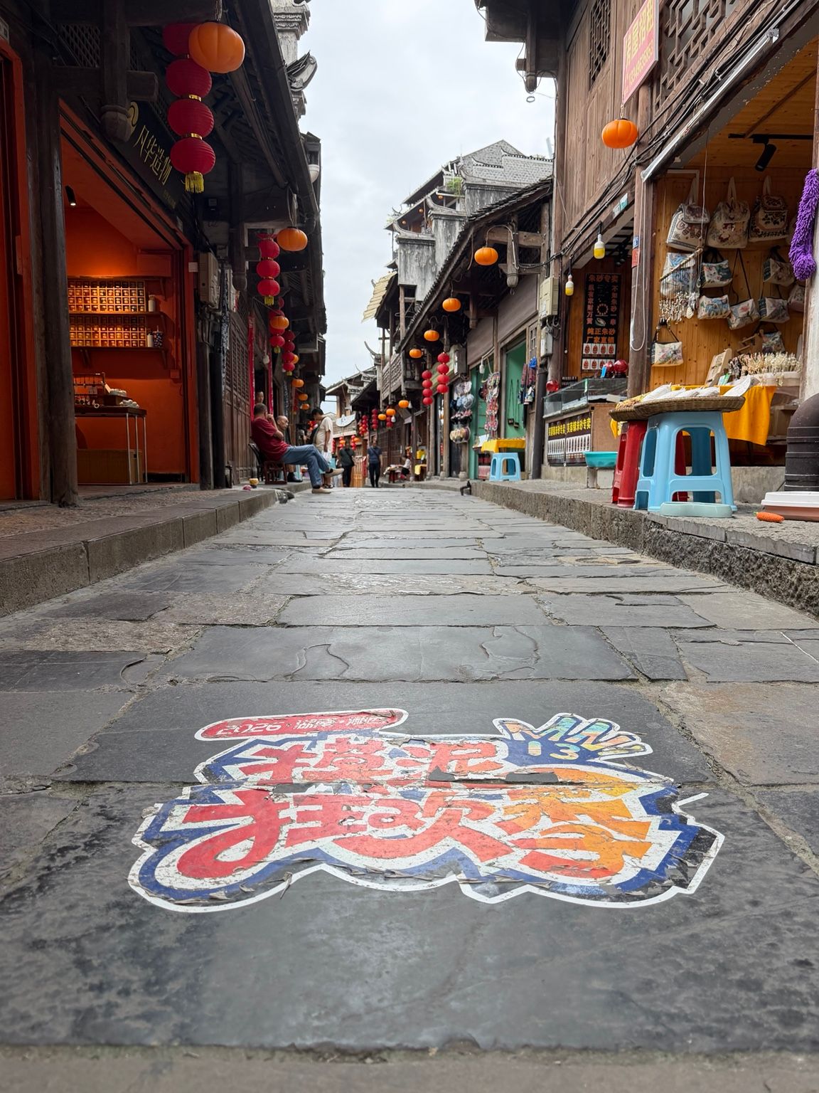 Rue pavée de Furong Town bordée de boutiques traditionnelles et de lanternes.