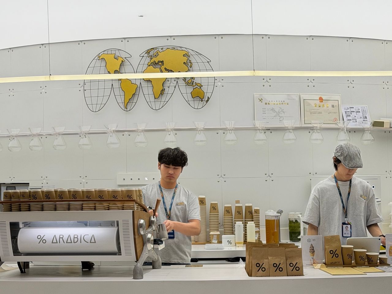 Comptoir % Arabica à Guangzhou Baiyun montrant le logo sur la machine, les gobelets, les sacs et plusieurs éléments du service.