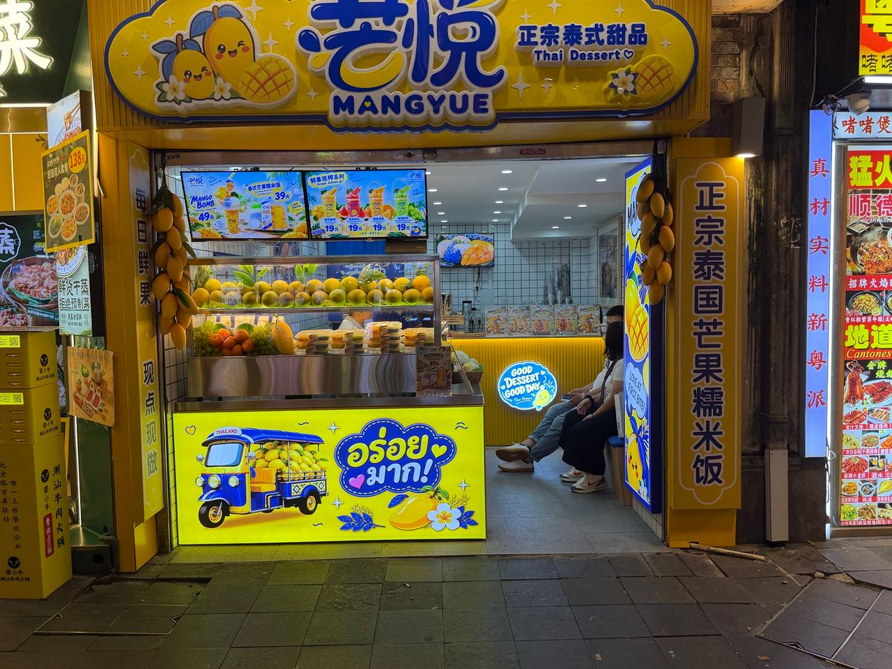 Façade réelle de MANGYUE en Chine, enseigne jaune et bleue consacrée aux desserts thaïlandais et à la mangue.