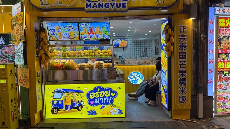 Façade réelle de MANGYUE en Chine, enseigne jaune et bleue consacrée aux desserts thaïlandais et à la mangue.