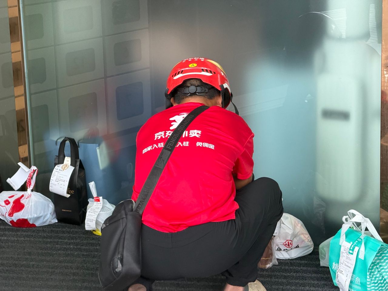 Livreur de repas JD photographié devant un bâtiment en Chine.