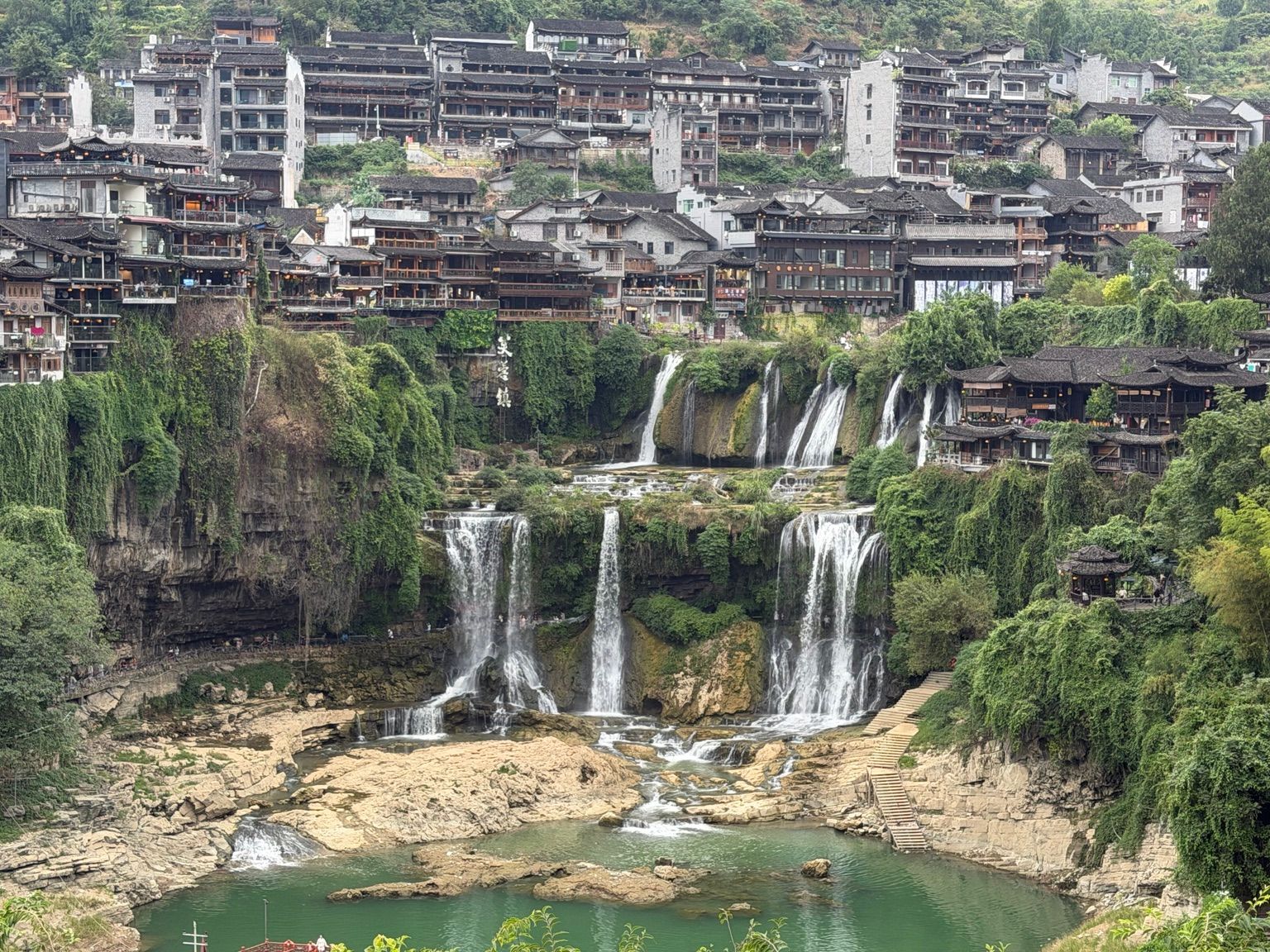 Vue panoramique de Furong Town dans le Hunan, avec la cascade au centre et les maisons traditionnelles construites au-dessus de la falaise.