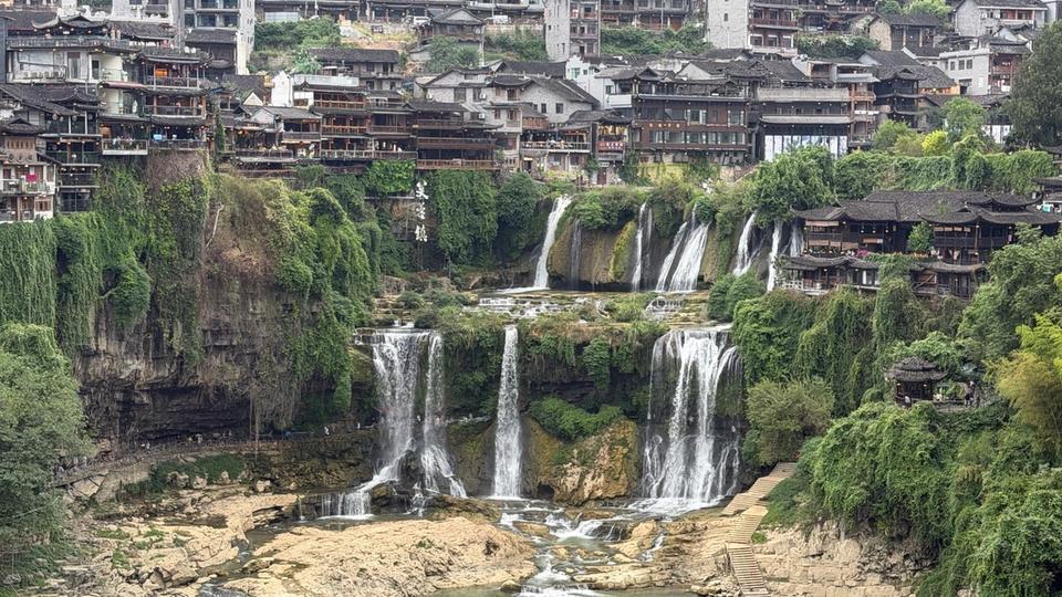 Vue panoramique de Furong Town dans le Hunan, avec la cascade au centre et les maisons traditionnelles construites au-dessus de la falaise.