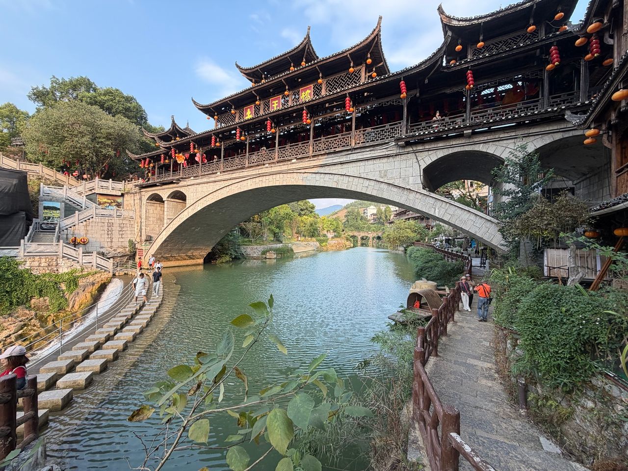 Grande passerelle traditionnelle de Furong Town au-dessus de l’eau, avec lanternes et architecture en bois.