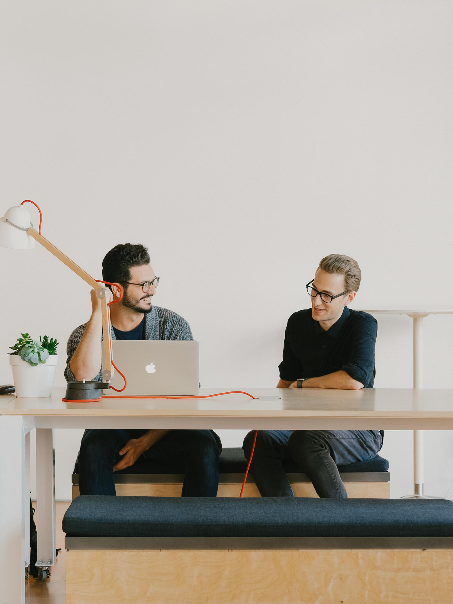 Two people sitting at a desk with a laptop