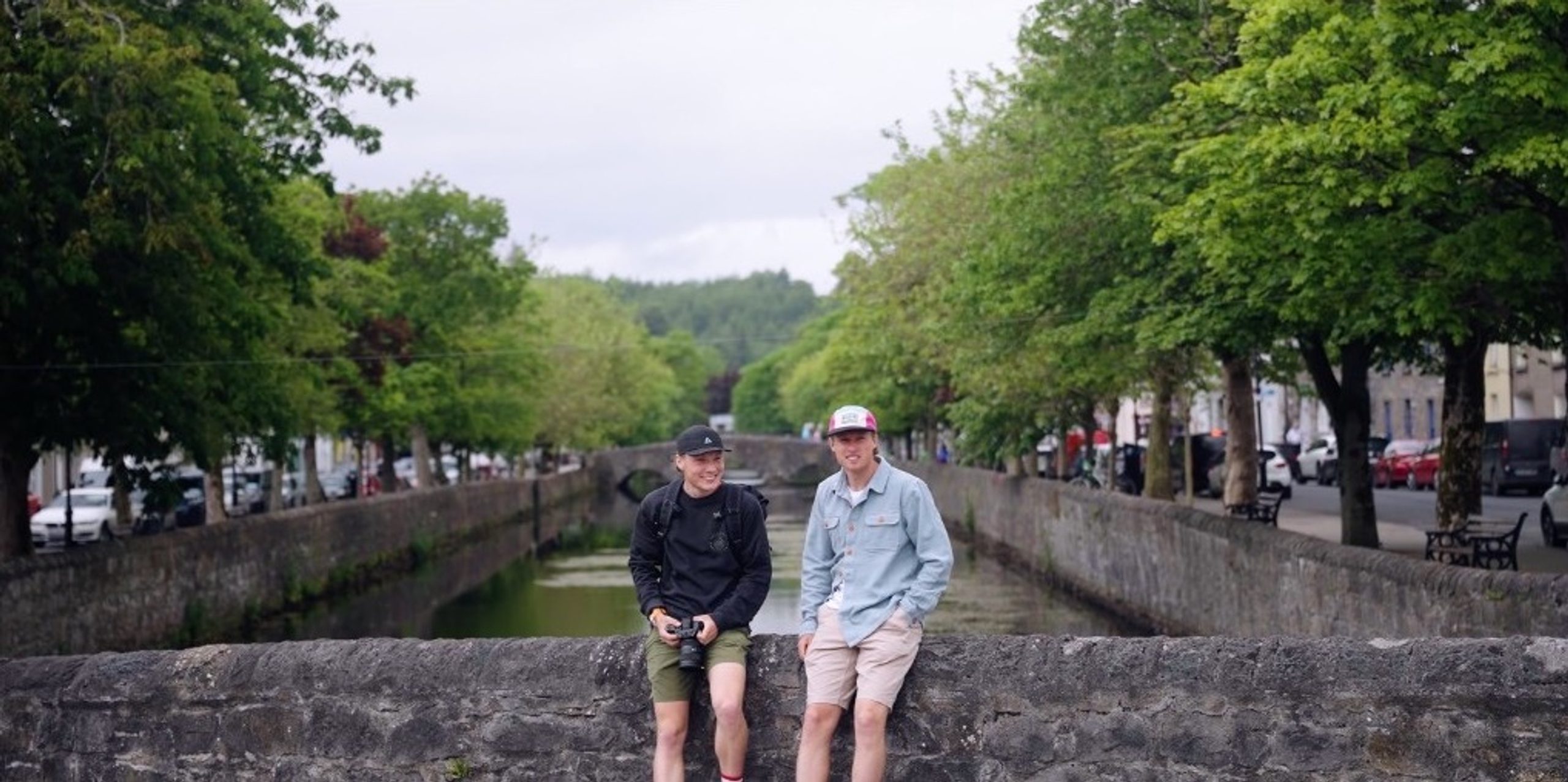 Connall and Matthew sitting on a stone bridge over a canal.