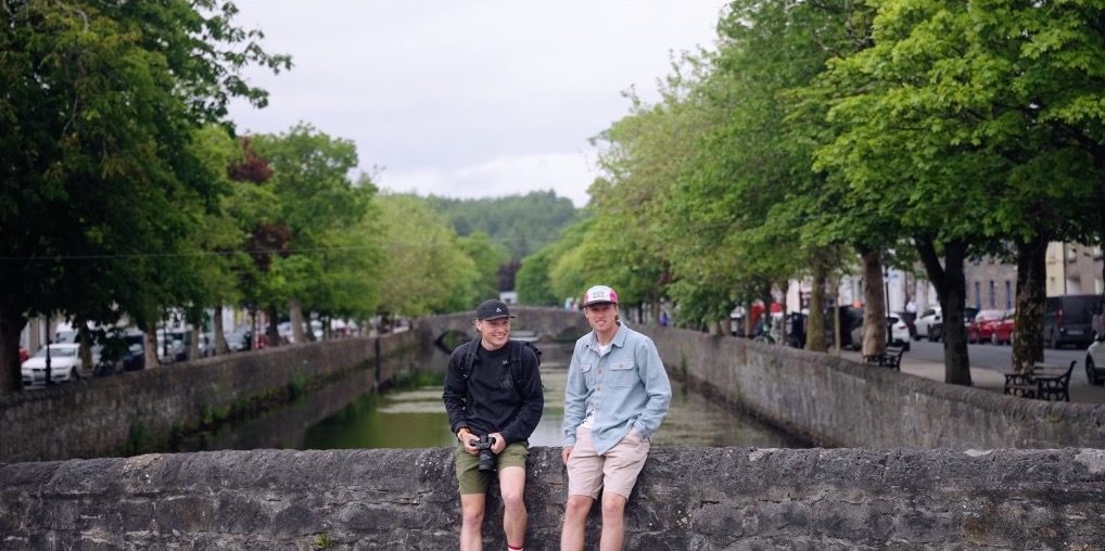 Connall and Matthew sitting on a stone bridge over a canal.