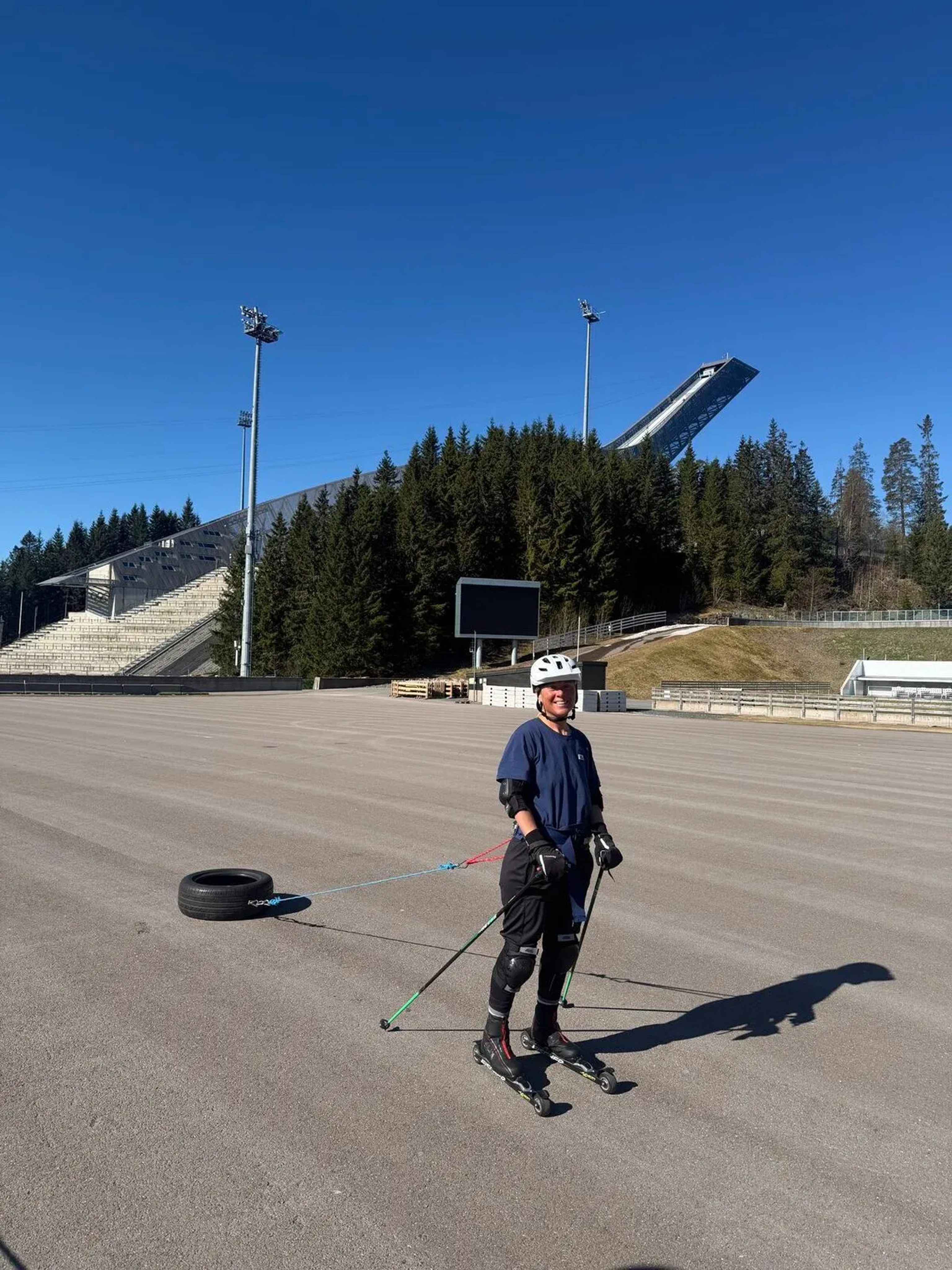Person on roller skis towing a tyre across tarmac during training in Oslo