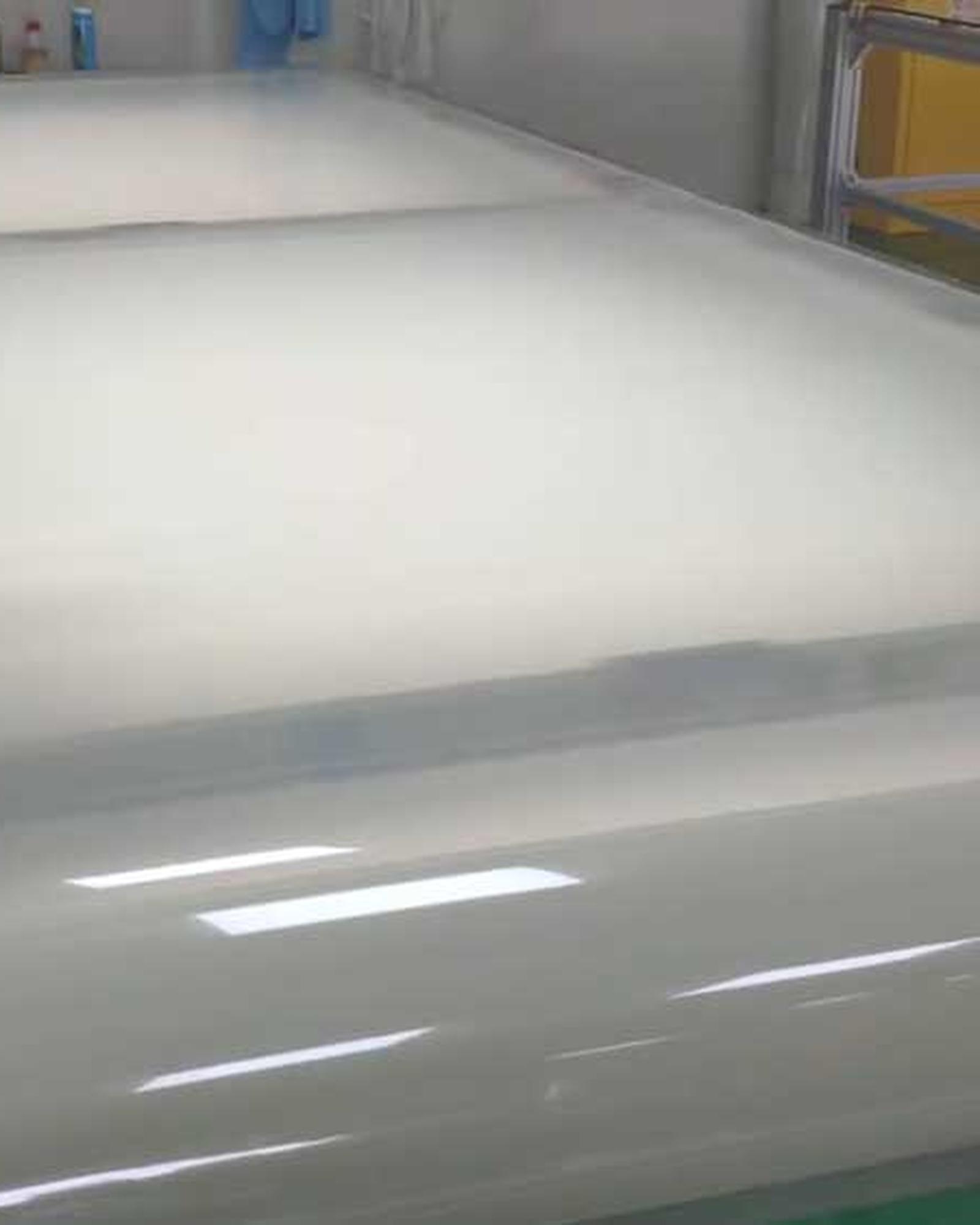 A wide sheet of clear protective film on a production line