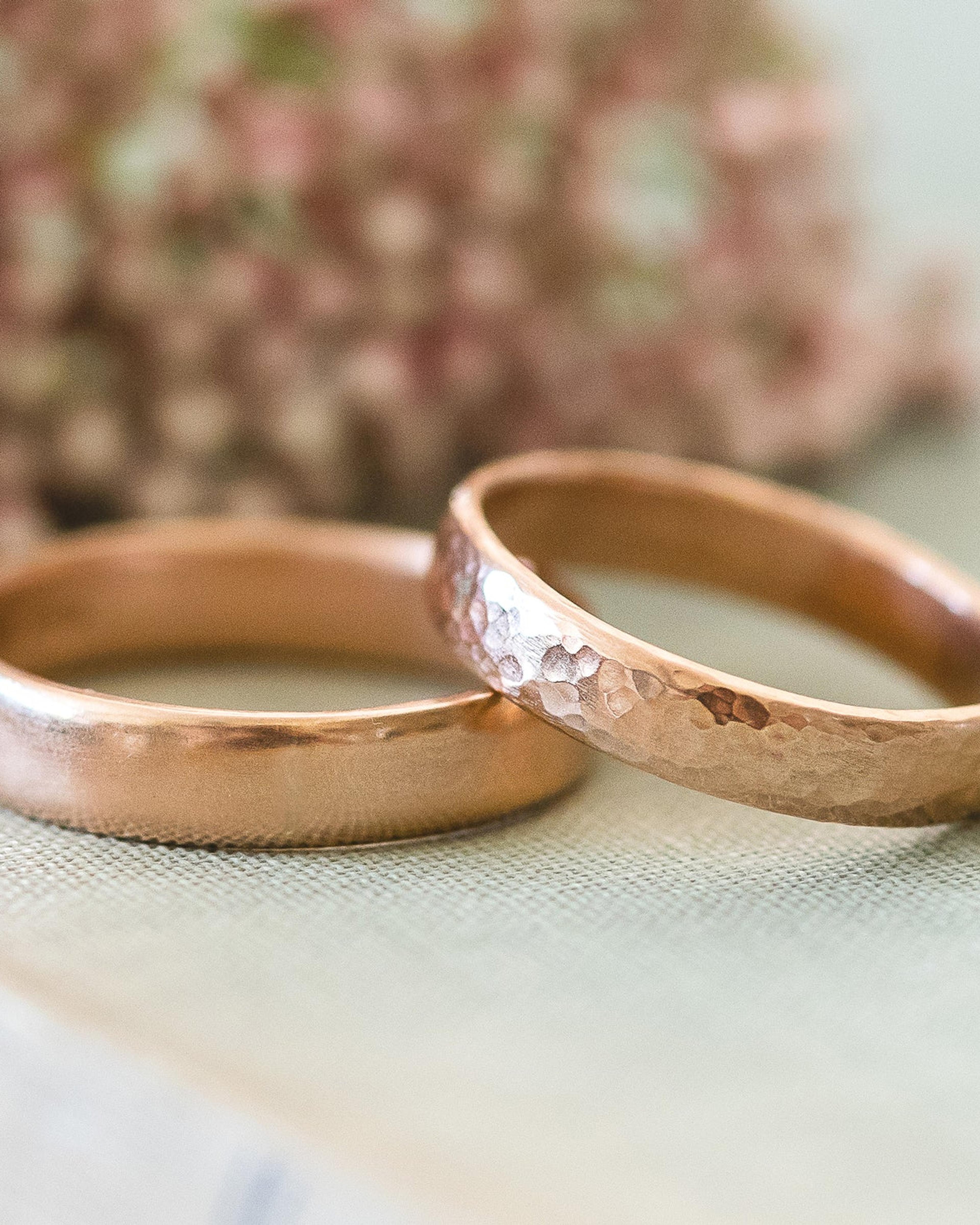 Two rose gold rings, one polished and one hammered, resting on linen