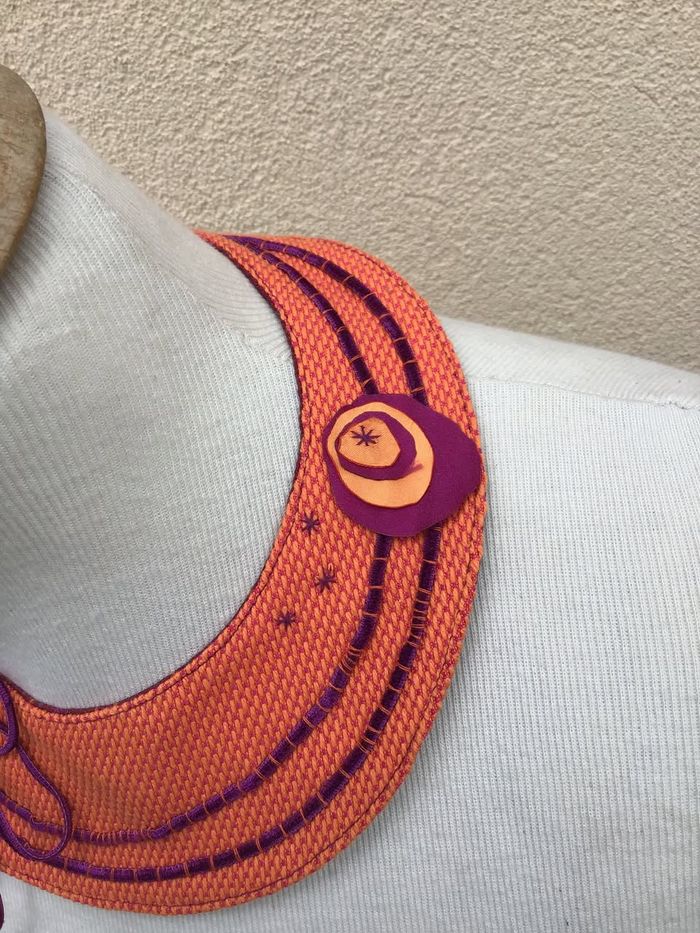 Col plastron orange brodé de violet