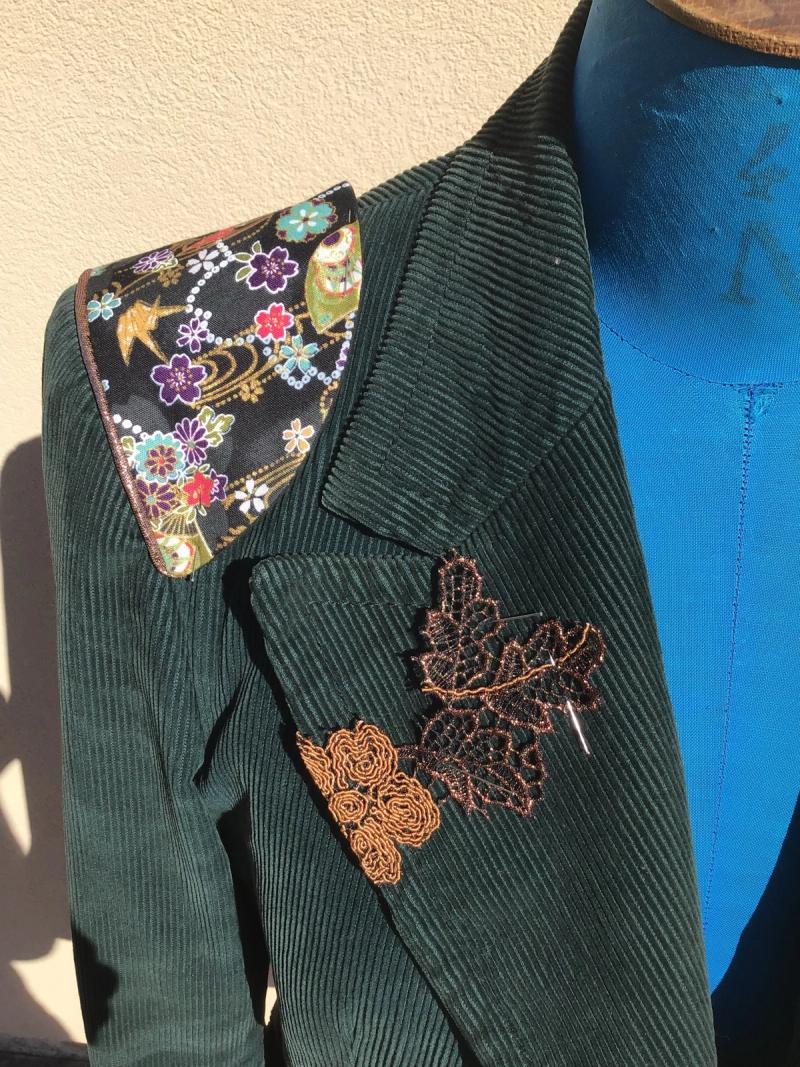 Détail de l’épaule : tissu fleuri et feuilles en dentelle sur le velours