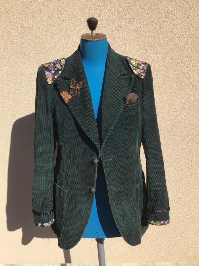 Veste en velours vert sur mannequin, épaulettes en tissu fleuri et broderies sur le revers