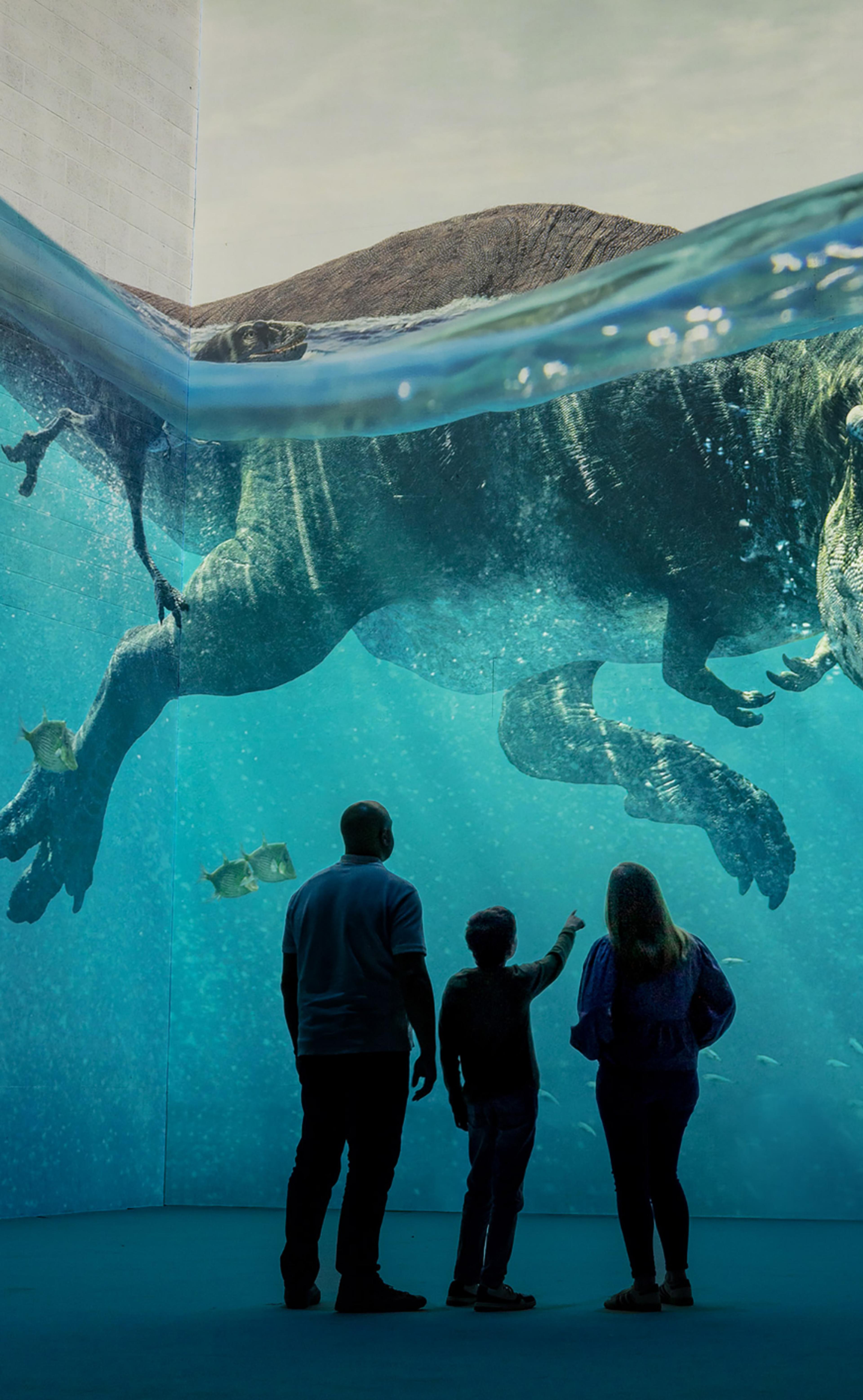 Familj tittar på t-rex som simmar i vattnet framför dem