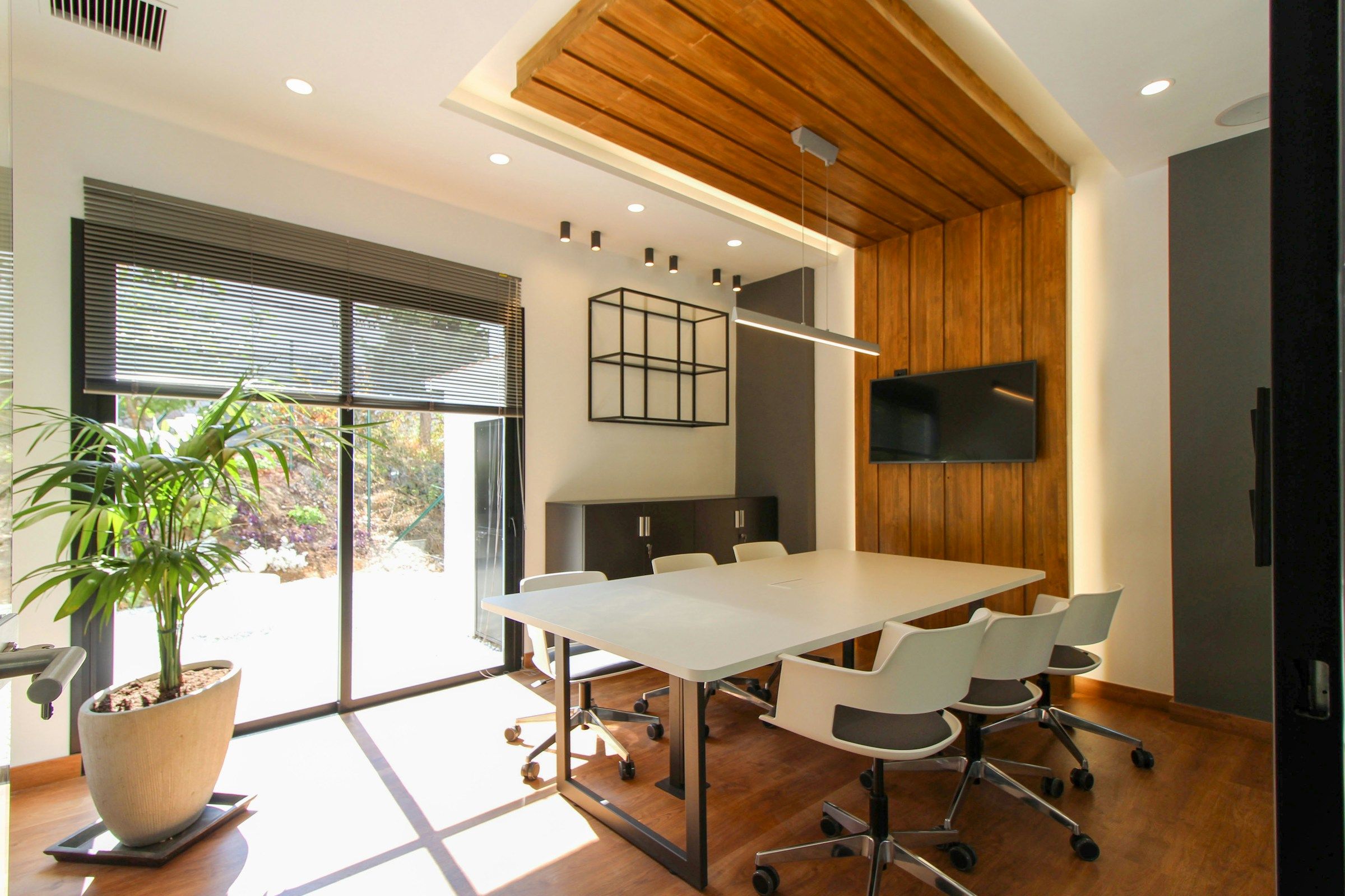 Daylight across a meeting table in an office with timber walls and large windows.