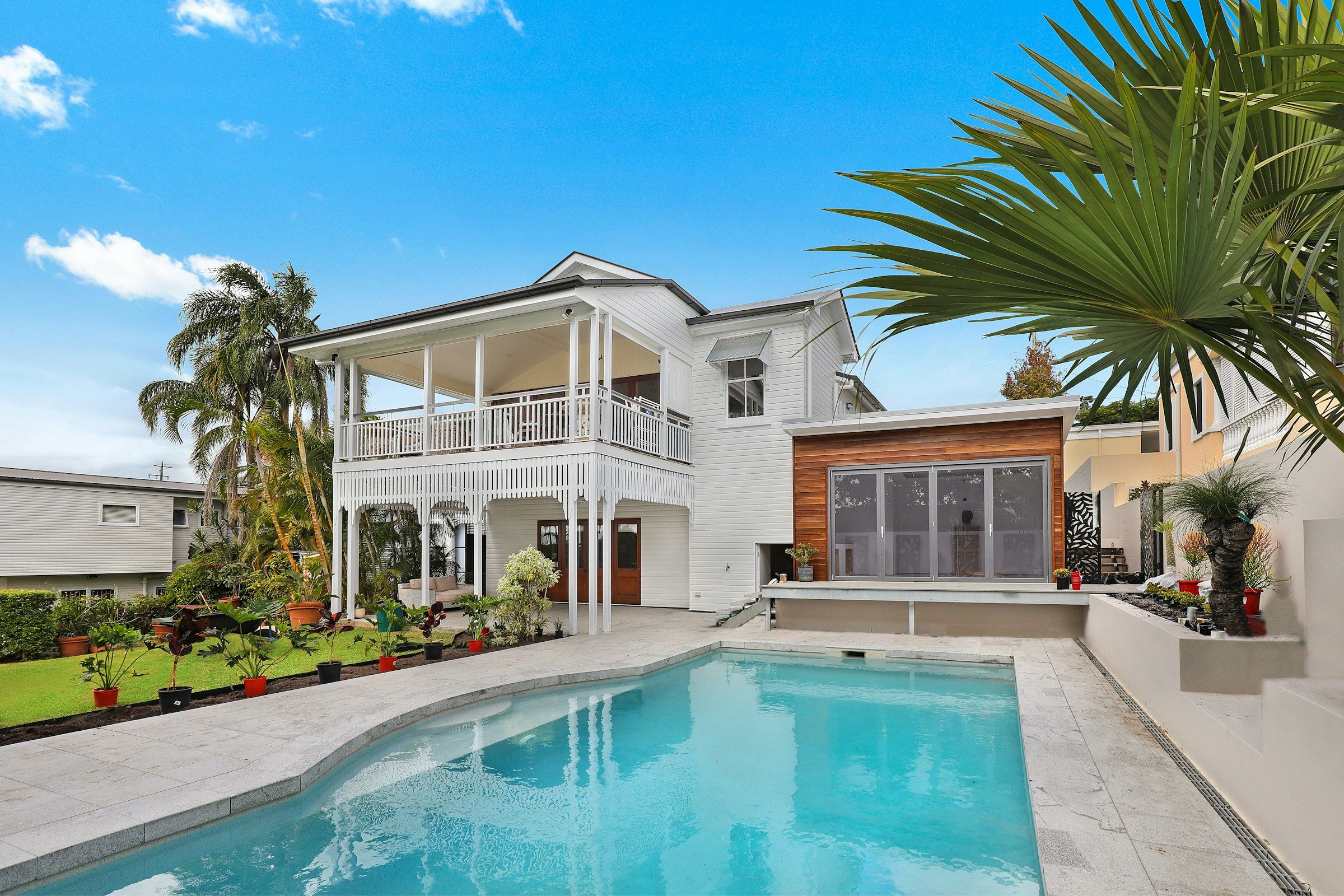 White two-story residence with a veranda, landscaped courtyard, and swimming pool.