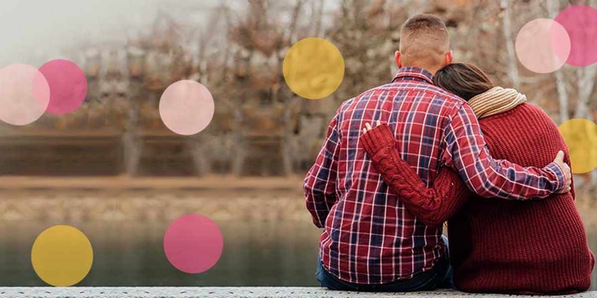 Couple sitting by the water with the woman leaning on the man's shoulder, both wearing cozy sweaters with soft colored circles overlaid.