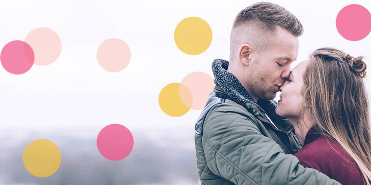 Couple embracing in the cold, touching foreheads and smiling softly, with pink and yellow confetti circles over a pale background.