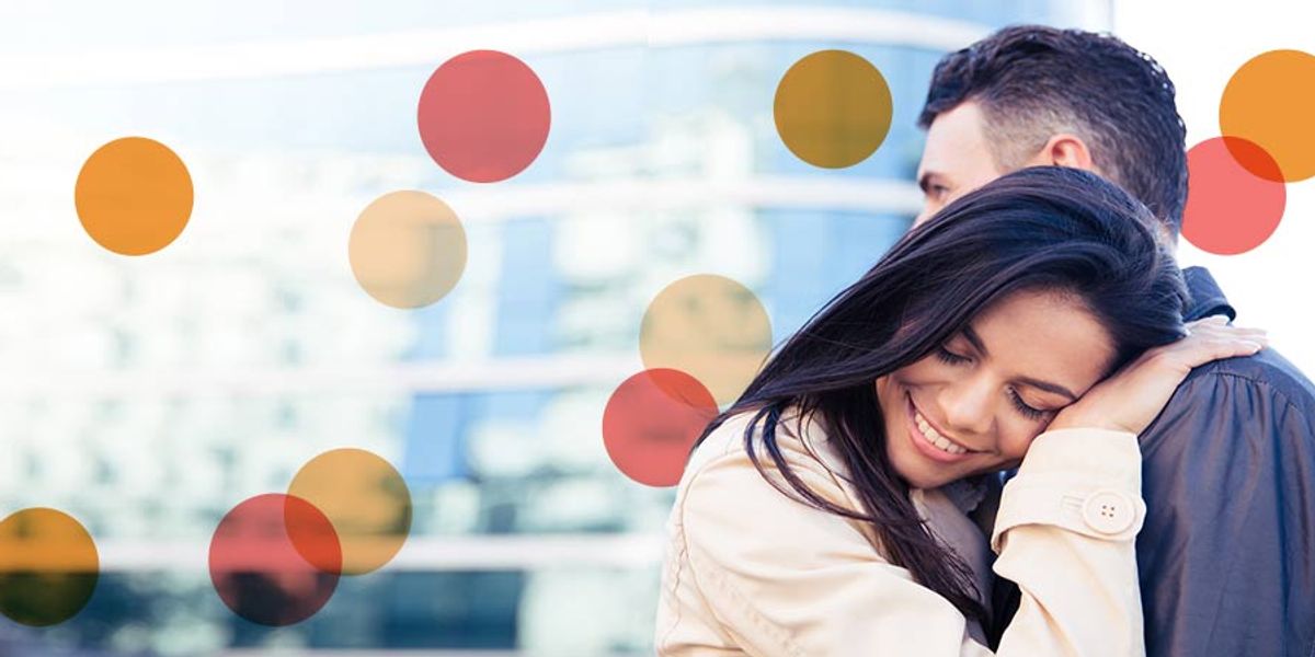 Woman smiling with her head resting on her partner’s shoulder, sharing a peaceful moment together