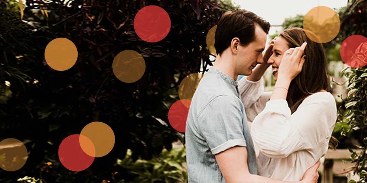 Couple smiling and holding each other closely in a lush garden, sharing a tender moment