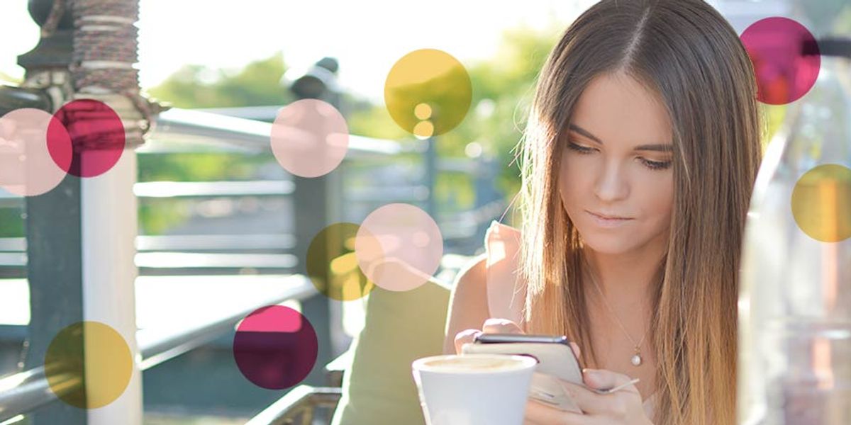 Woman sitting outdoors at a café, looking down at her phone while holding a cup of coffee, with colorful circles overlaid on the image.