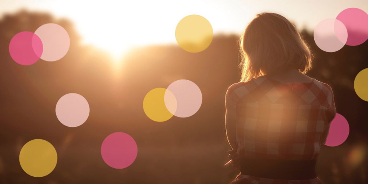 Woman standing outdoors at sunset with her back turned, surrounded by soft pink and yellow circles overlaid on the image.
