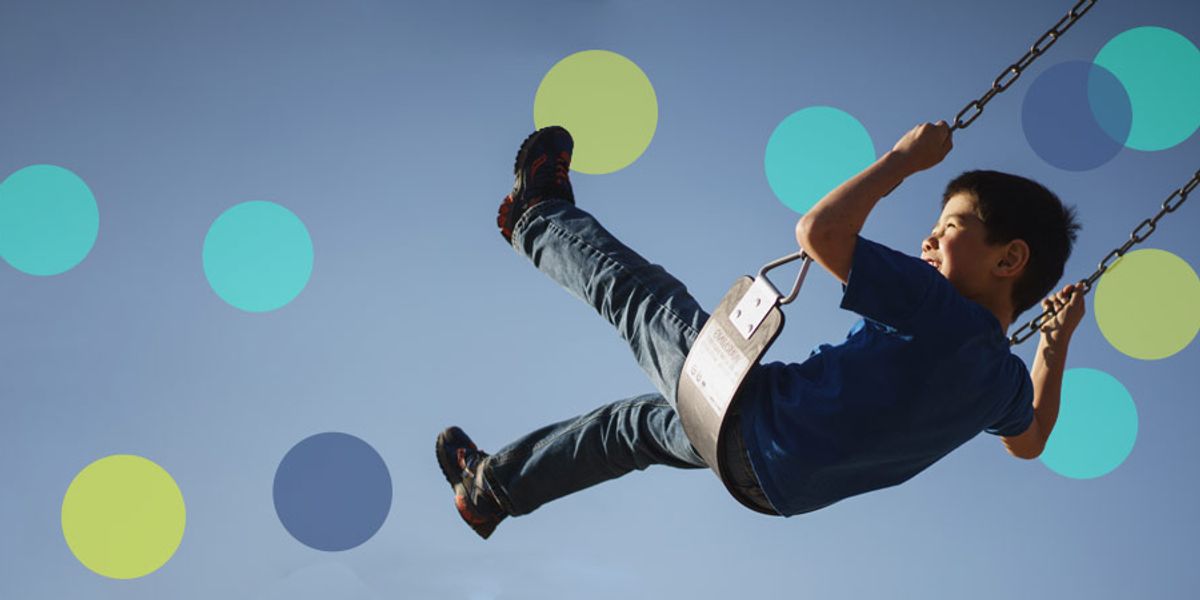 Boy laughing as he swings high into the sky on a playground swing, with colorful circles overlaid on the image.