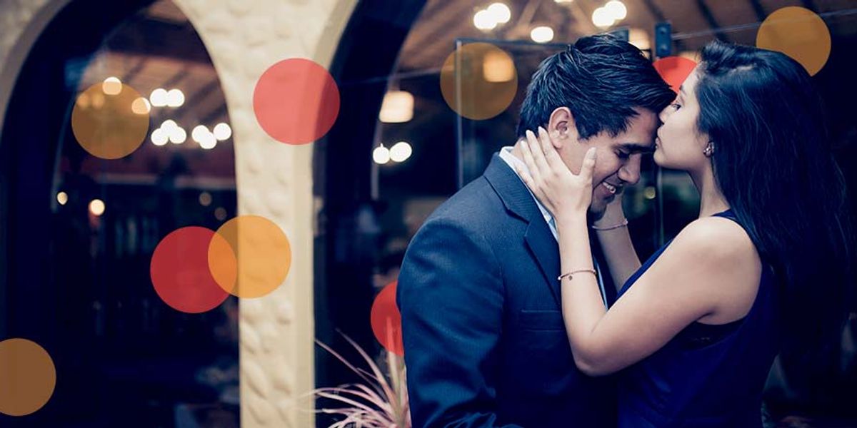 Couple dressed up at night as she kisses his forehead, sharing an intimate and tender moment