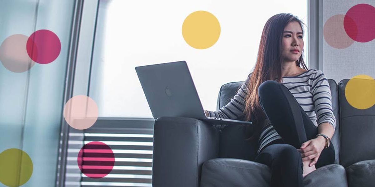 Woman sitting on a couch with a laptop on her lap, looking thoughtfully to the side, with soft pink and yellow circles overlaid on the image.