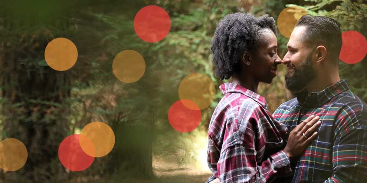Couple smiling and touching foreheads in a forest, sharing an intimate moment