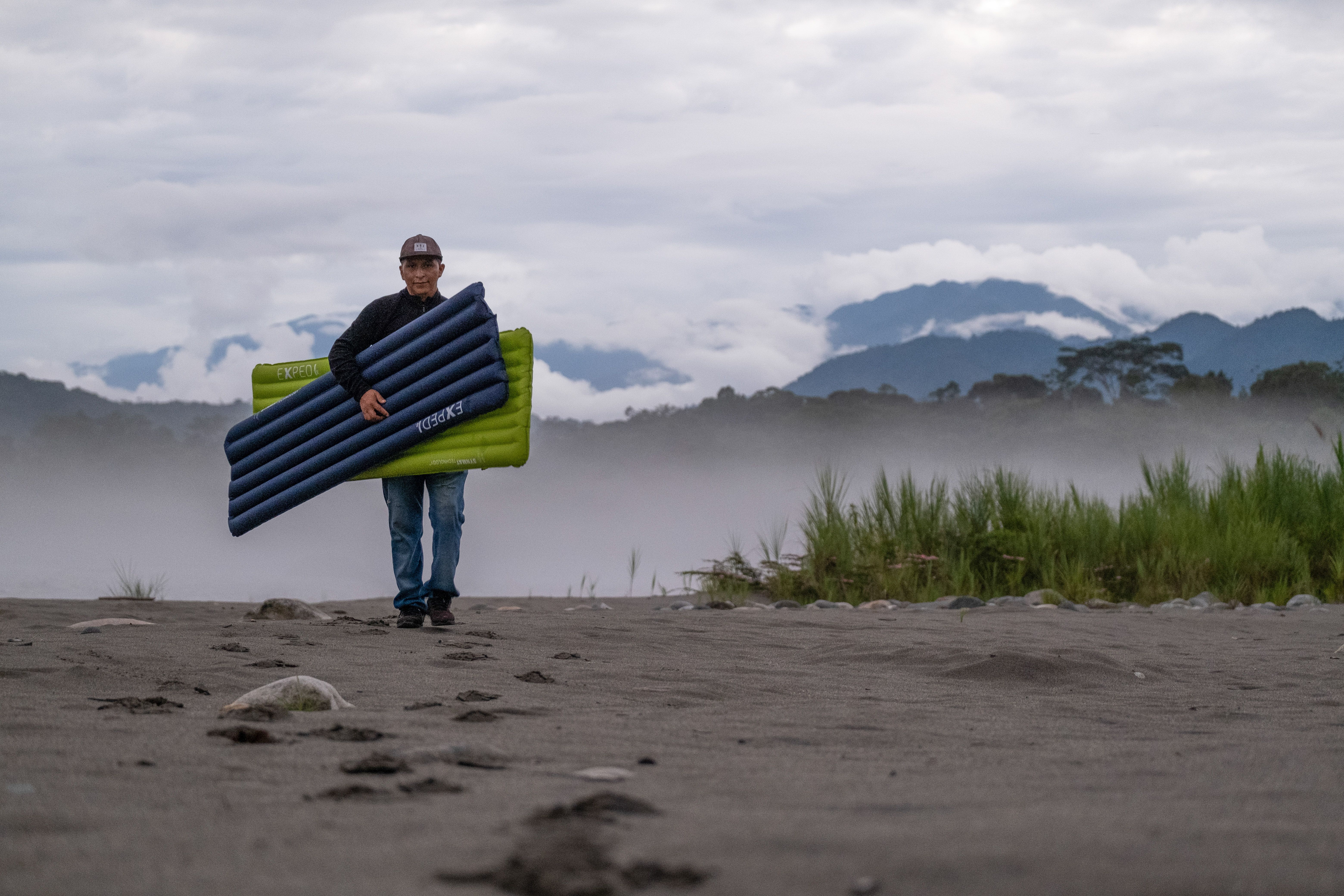 Man carrying exped sleeping pads in nature