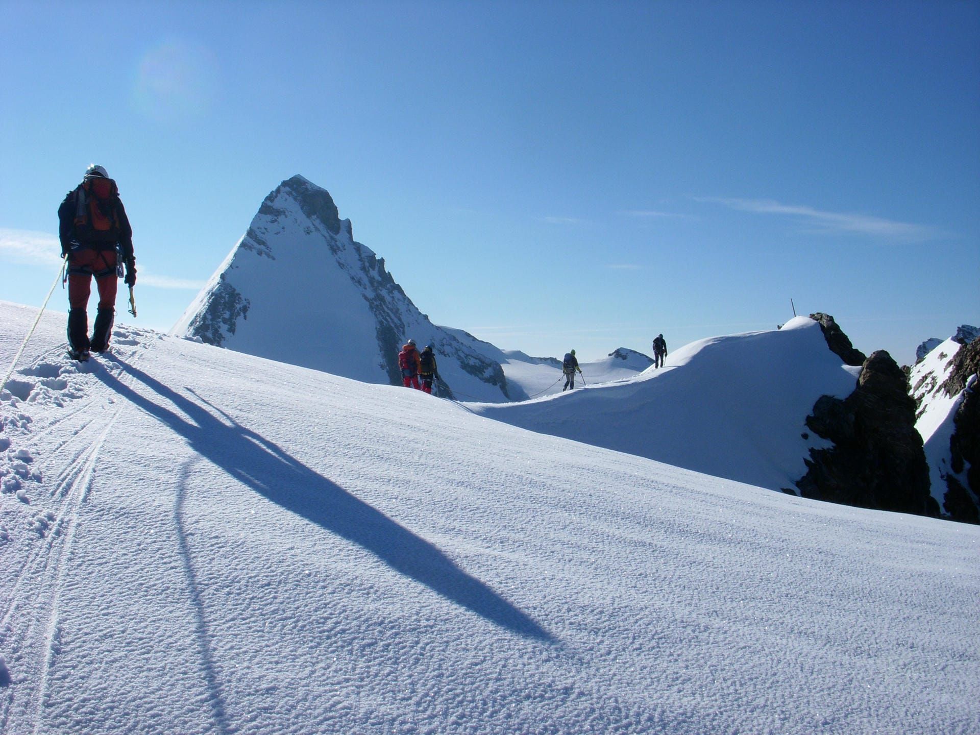 A group of mountaineers hiking along the edge of a snowy mountain.