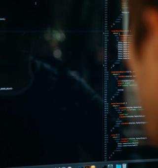 En mjukvaruutvecklare som tittar på en skärm med programmeringskod.