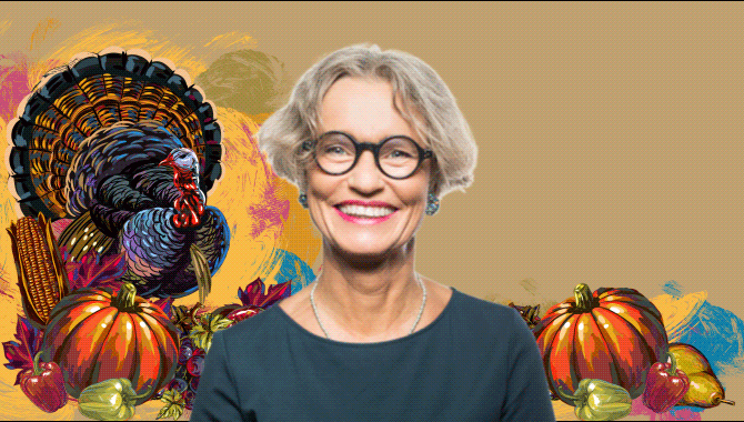 Older woman standing in front of a beige background with an oil painting of a turkey blinking and pumpkins and peppers