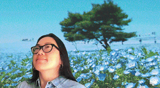 青いネモフィラの花畑で風に吹かれる女性